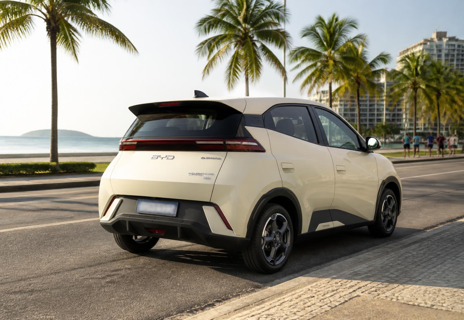 BYD Dolphin Mini elétrico creme visto de trás em avenida à beira-mar ensolarada